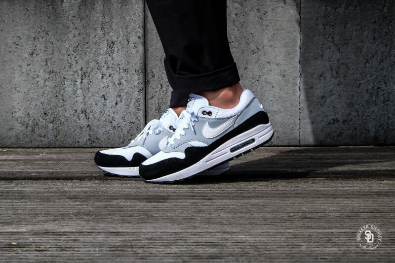 Photo d'une paire de baskets Nike Air Max 1 blanches, grises et noires, portées par un adolescent