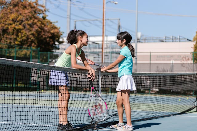 Deux ados discutant sur un cours de tennis.